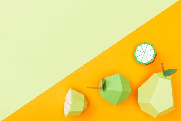 Top view of handmade colorful origami fruits on orange and green with copy space — Stock Photo