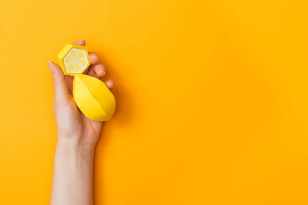 Partial view of young woman holding paper lemons isolated on orange with copy space — Stock Photo