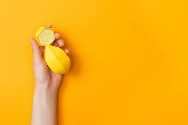 Vue partielle de la jeune femme tenant des citrons en papier isolés sur orange avec espace de copie — Photo de stock