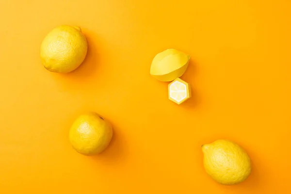 Vue du dessus des citrons en papier faits à la main et des citrons mûrs entiers isolés sur orange — Photo de stock