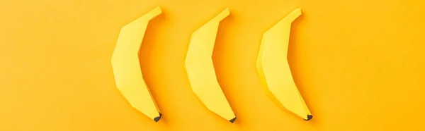 Plano panorámico de plátanos de papel amarillo dispuestos en naranja - foto de stock