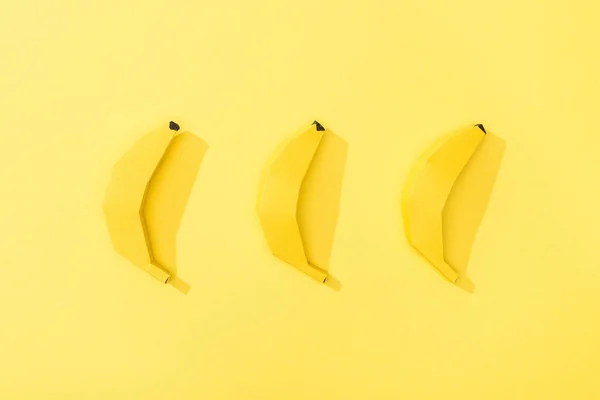Vue du dessus des bananes en papier à la main disposées en rangée sur jaune — Photo de stock