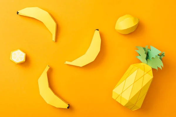 Vista superior de limones de papel hechos a mano, plátanos y piña aislados en naranja - foto de stock