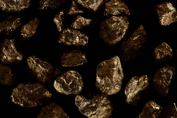 Top view of scattered shiny golden stones isolated on black — Stock Photo