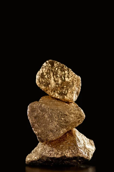 Stack of gold textured stones isolated on black — Stock Photo