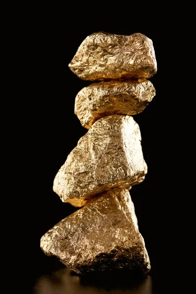 Four golden textured shiny stones isolated on black — Stock Photo