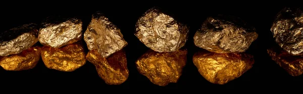 Plano panorámico de piedras brillantes de oro en fila con reflejo aislado en negro - foto de stock