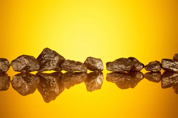Gold shiny textured stones with reflection and yellow back light — Stock Photo