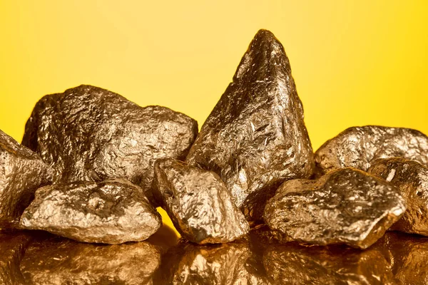 Pilha de pedras brilhantes de ouro com reflexão isolada no amarelo — Fotografia de Stock