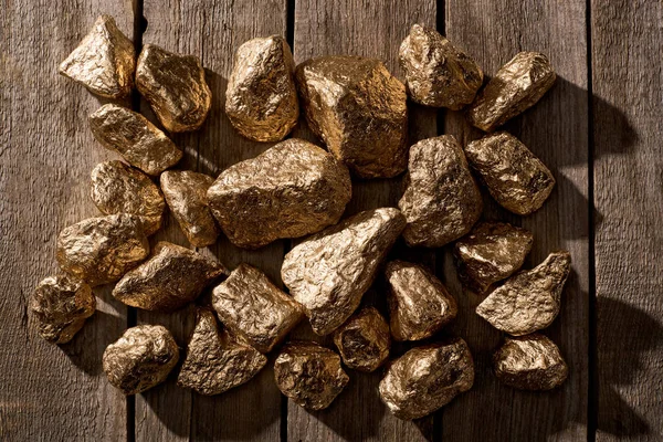 Vue de dessus des pierres brillantes d'or sur la table en bois à la lumière du jour — Stock Photo