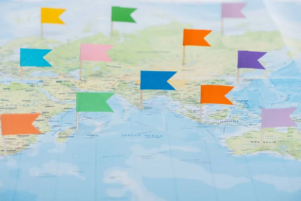 Bandeiras coloridas de papelaria presas no mapa do mundo — Fotografia de Stock