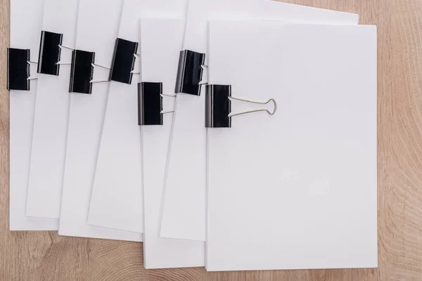 Vue du dessus des piles de papier blanc avec pinces à reliure métallique et espace de copie sur la table en bois — Photo de stock