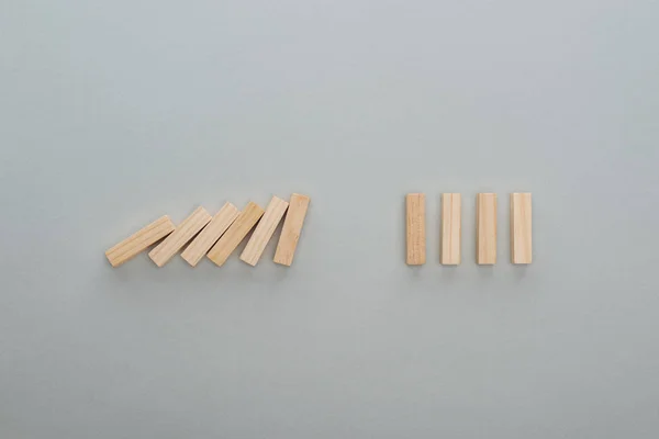 Vista superior de bloques de madera que caen aislados en gris, concepto de efecto dominó - foto de stock