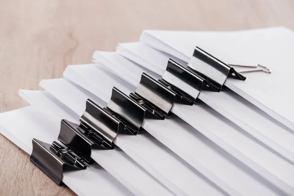 Arranged stacks of blank paper with metal binder clips on table — Stock Photo