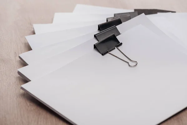 Stacks of blank paper with metal binder clips and copy space on wooden desk — Stock Photo