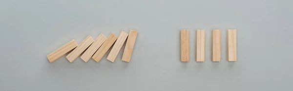 Panoramic shot of of falling wooden blocks isolated on grey, domino effect concept — Stock Photo