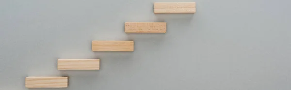 Plano panorámico de bloques de madera que simbolizan escalera de carrera aislado en gris con espacio de copia - foto de stock