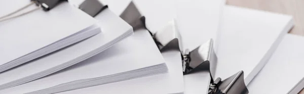 Panoramic shot of stacks of blank paper with metal binder clips — Stock Photo