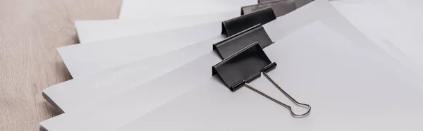 Panoramic shot of stacks of blank paper with metal binder clips — Stock Photo