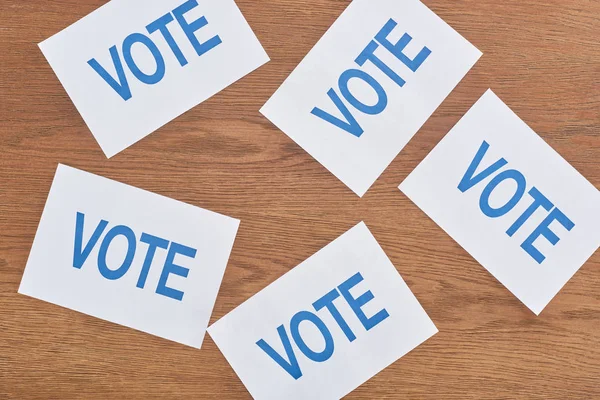 Vista superior de cartões brancos com letras de voto espalhadas na mesa de madeira — Fotografia de Stock