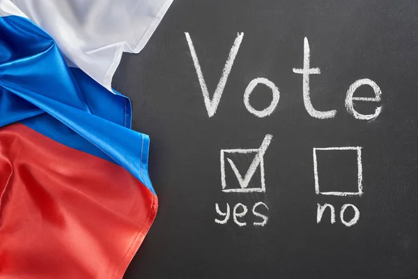 Top view of vote lettering and check mark near yes word on black chalkboard near European flag — стоковое фото