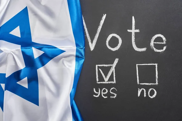 Top view of vote word and check mark near yes word on black chalkboard near flag of Israel — Stock Photo