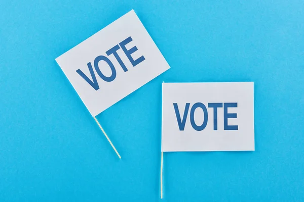 Vista superior de bandeiras brancas com letras de voto no fundo azul — Fotografia de Stock