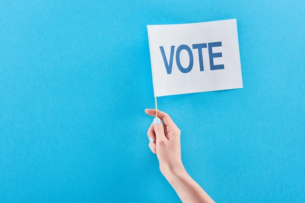 Partial view of woman holding white flag with vote lettering on blue background with copy space — Stock Photo