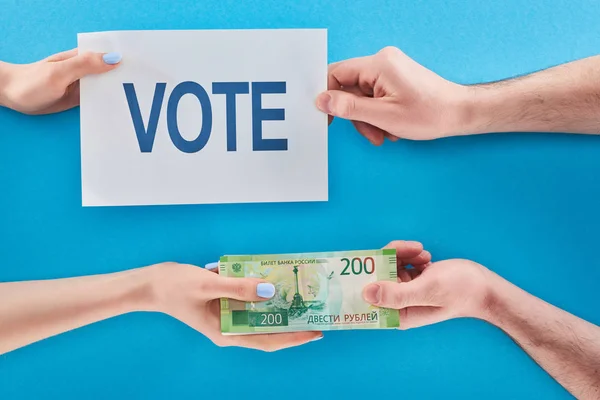 Vue partielle de la femme donnant pot de vin pour voter en roubles à l'homme sur fond bleu — Photo de stock