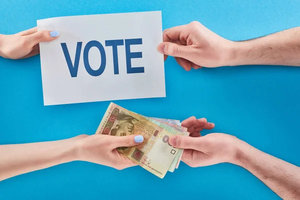 Partial view of woman giving ukrainian hryvni for vote to man on blue background — Stock Photo