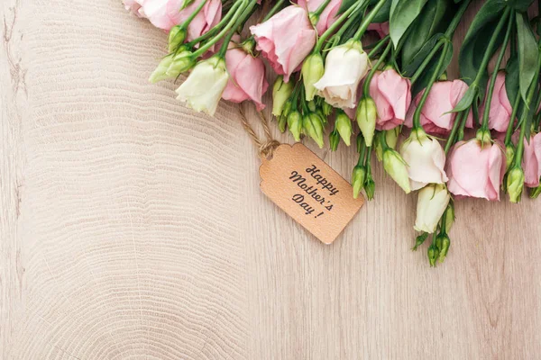 Vista dall'alto di fiori di eustoma con felice mamma giorno etichetta di carta su tavolo in legno con spazio copia — Foto stock
