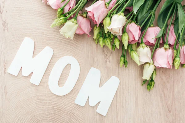 Vista superior de flores de eustoma con palabra de mamá en la mesa de madera - foto de stock