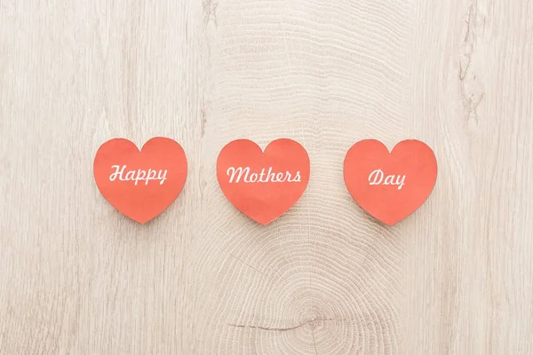 Top view of red paper cards with happy mothers day writing on wooden table — Stock Photo