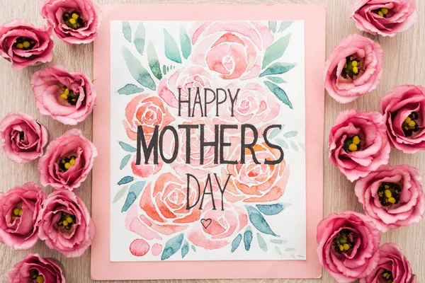 Vista superior de flores eustoma e cartão com feliz dia das mães escrevendo na mesa — Fotografia de Stock