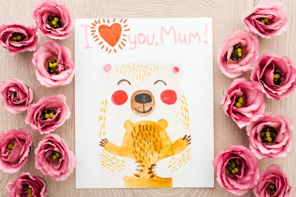 Top view of pink eustoma flowers and card with i love you mum words on wooden table — Stock Photo