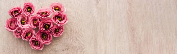 Plan panoramique de signe de coeur fait de fleurs d'eustomes roses sur table en bois avec espace de copie — Photo de stock