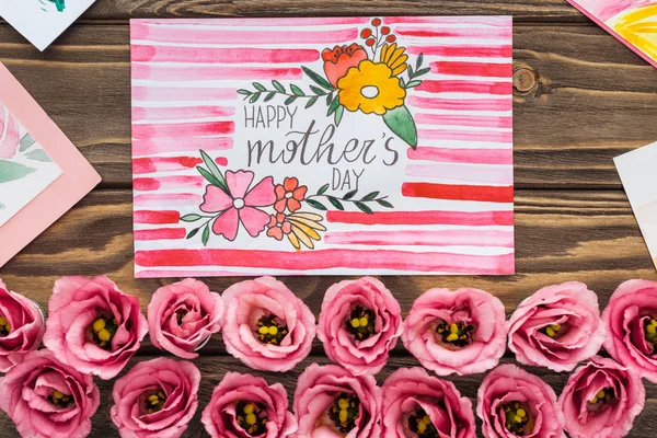 Вид зверху на квіти еустоми і листівки з щасливими матерями привітання на дерев'яному столі — стокове фото