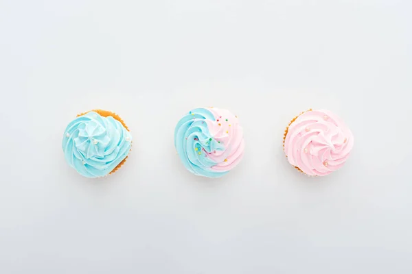 Vue de dessus de délicieux cupcakes colorés avec des saupoudres en rangée isolé sur blanc — Photo de stock