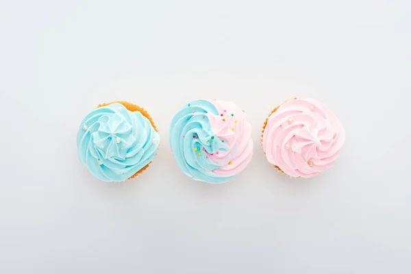 Vista superior de deliciosos cupcakes coloridos com polvilhas em linha Isolado em branco — Fotografia de Stock