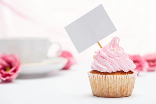 Selective focus of delicious pink cupcake decorated with sprinkles and blank card — Stock Photo