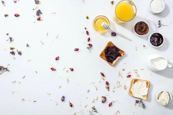 Draufsicht auf Toasts mit Marmelade und Frischkäse in der Nähe von Glas Orangensaft auf Weiß — Stockfoto