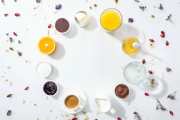 Top view of bowls with jam, honey, chocolate cream and cream cheese near glasses with drinks on white — Stock Photo