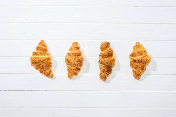 Flache Lage süßer und köstlicher Croissants auf weißer Oberfläche — Stockfoto