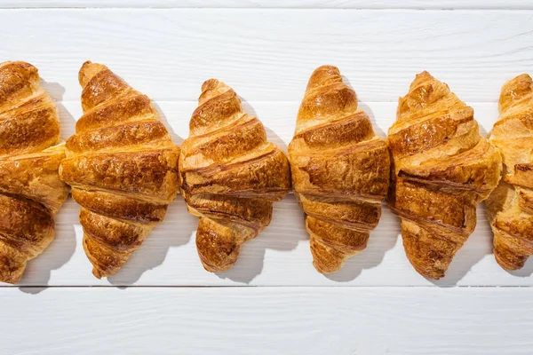 Vista dall'alto di croissant dolci, gustosi e freschi su superficie bianca — Foto stock