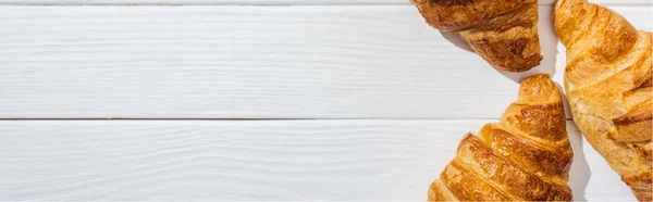 Plano panorámico de croissants sabrosos y frescos en la superficie blanca - foto de stock