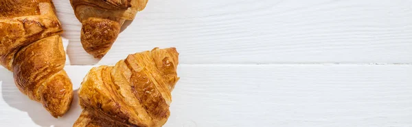 Panoramic shot of tasty croissants on white surface — Stock Photo