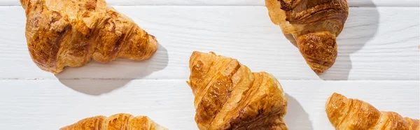 Tiro panorâmico de croissants saborosos e doces na superfície branca — Fotografia de Stock