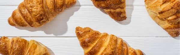 Plano panorámico de deliciosos croissants en la superficie blanca - foto de stock