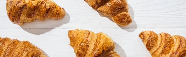 Tiro panorâmico de croissants deliciosos e doces na superfície branca — Fotografia de Stock