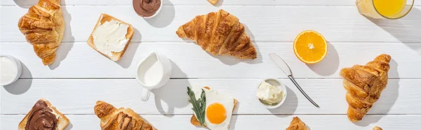 Tiro panorâmico de croissants doces perto de torradas saborosas e bebidas em branco — Fotografia de Stock